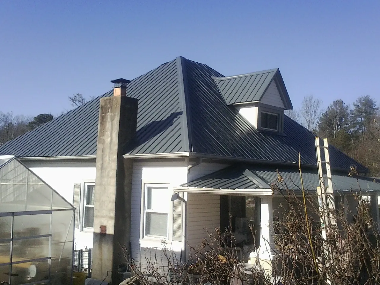 Dark blue standing seam metal roof on a white farmhouse with dormer — Slate & Tile Roof Repair by Roofing Brothers in Shartlesville