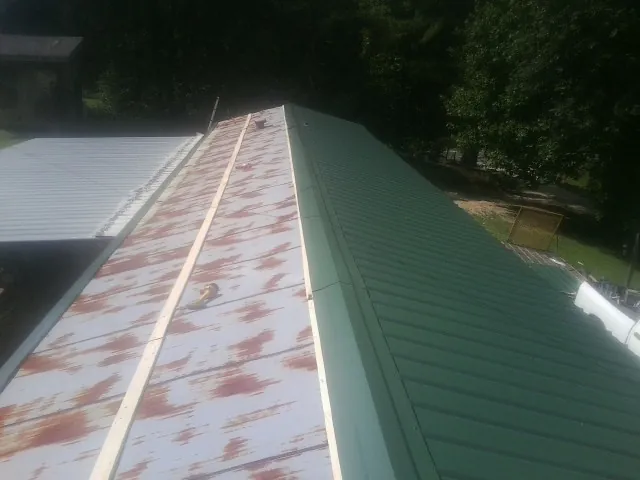 Old rusted panels beside newly installed green metal roofing — Wind Damage Roof Repair by Roofing Brothers in Shartlesville