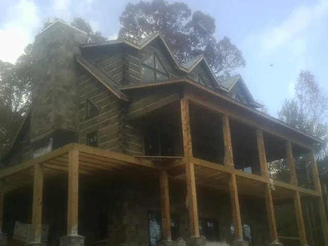 Stone chimney and dormers on a large log home with a timber porch in Shartlesville