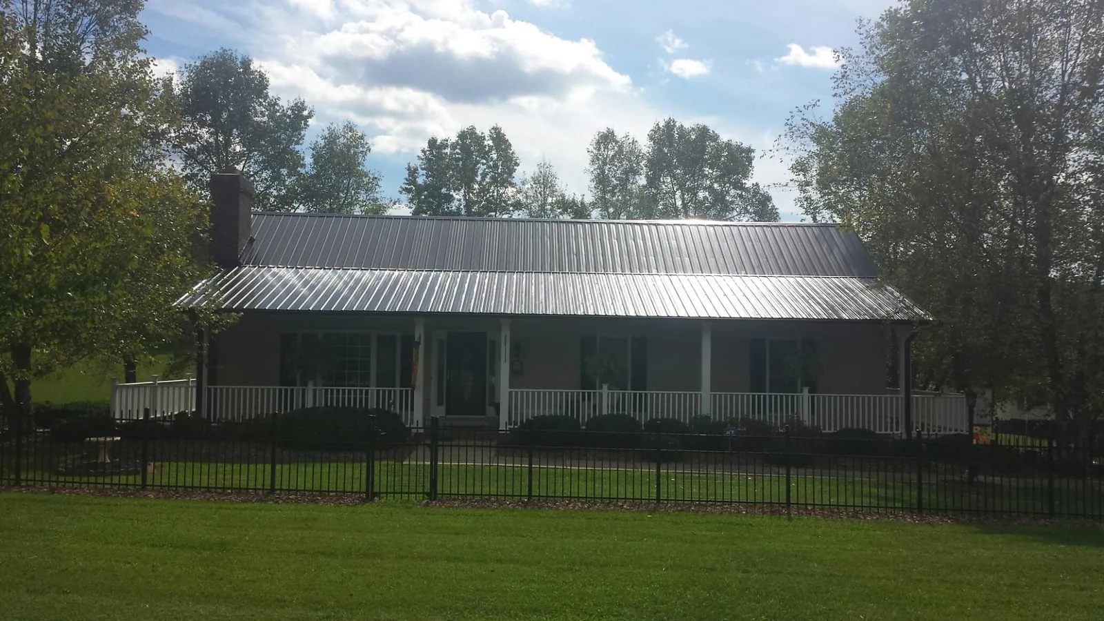 Gray metal roof on a brick ranch with a full width front porch — Gutter Guard Installation work by our crew in Shartlesville