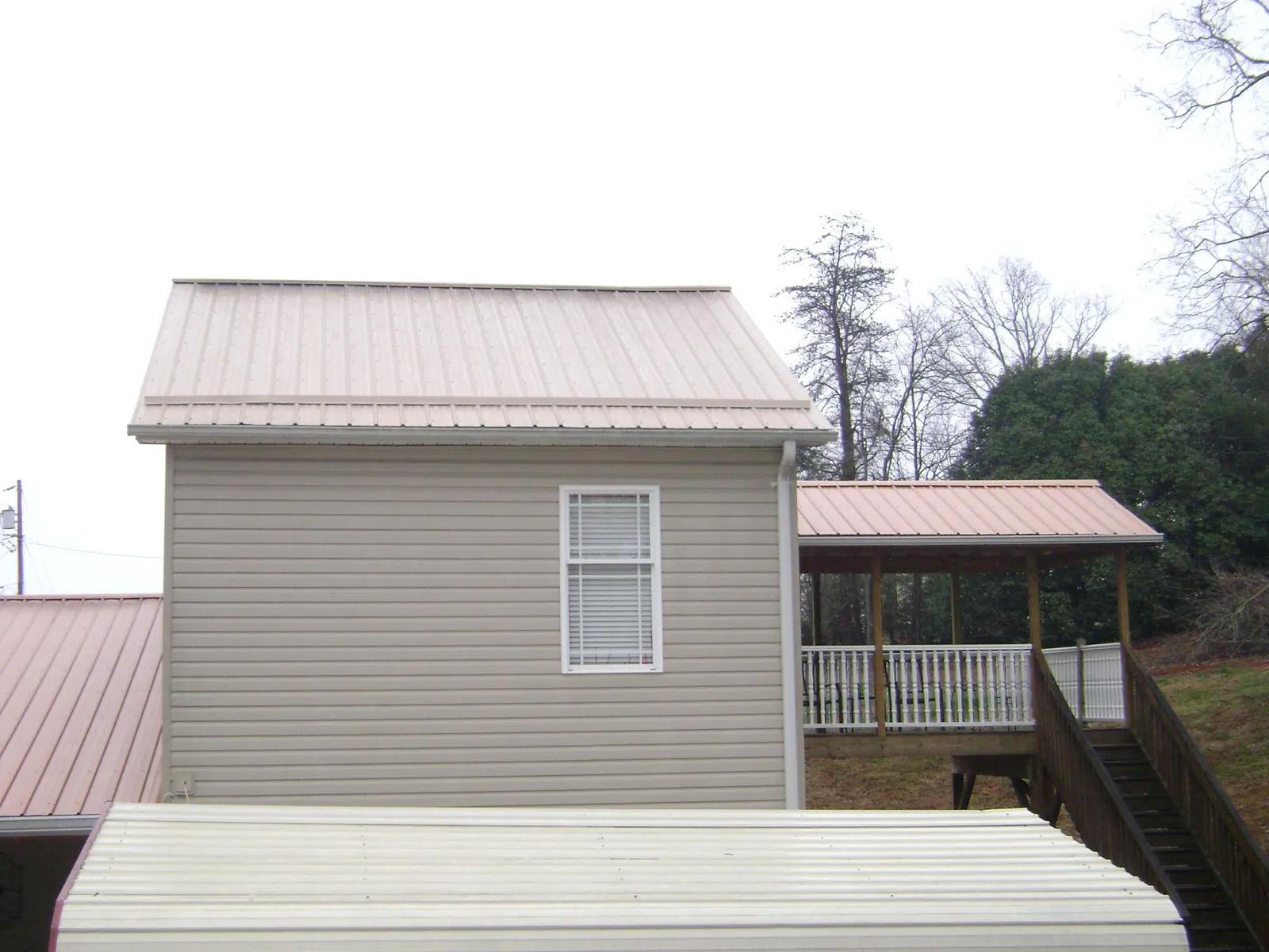Tan metal roofs on a two story addition and attached porch, from a Roof Replacement job in Shartlesville