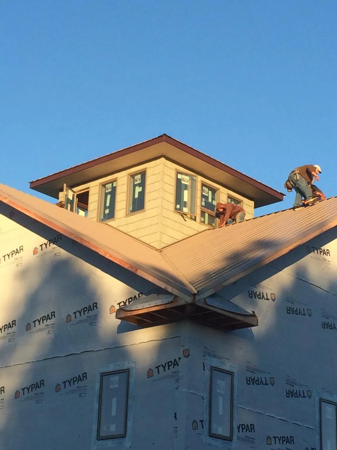 Roofers working around a rooftop cupola on a new metal roof at sunset — Roof Waterproofing in Shartlesville by Roofing Brothers
